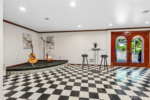 a living room with a black white checkered floor with a gaming machine and dining chairs