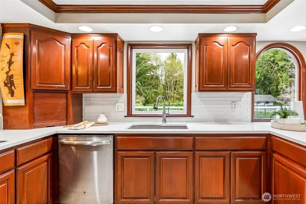 a kitchen with stainless steel appliances granite countertop a sink a window and cabinets