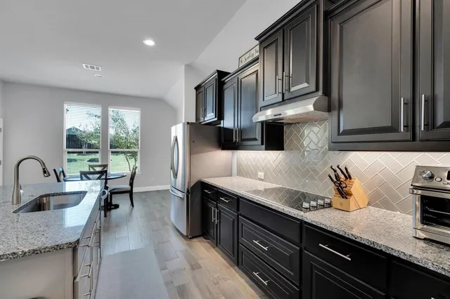 a kitchen with stainless steel appliances granite countertop a sink refrigerator and cabinets