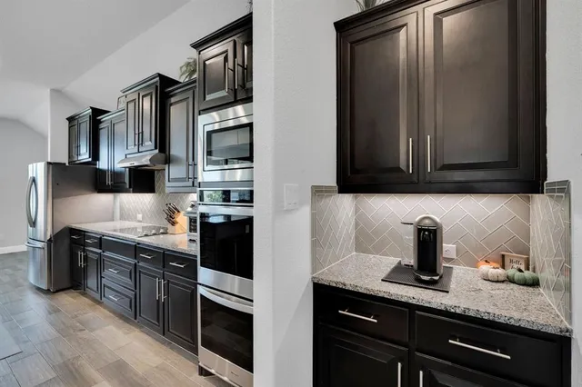 a kitchen with granite countertop a sink a stove and cabinets