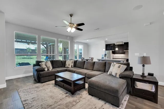 a living room with furniture a ceiling fan a rug and a window