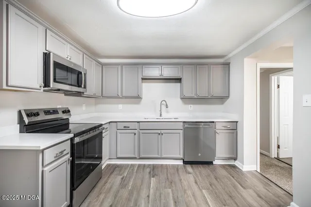 a kitchen with stainless steel appliances granite countertop a stove top oven a sink dishwasher and a microwave oven on the blue kitchen countertops with wooden floor