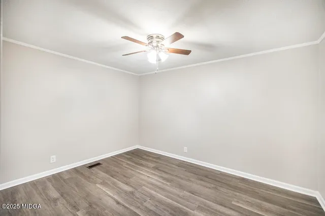 an empty room with wooden floor and fan
