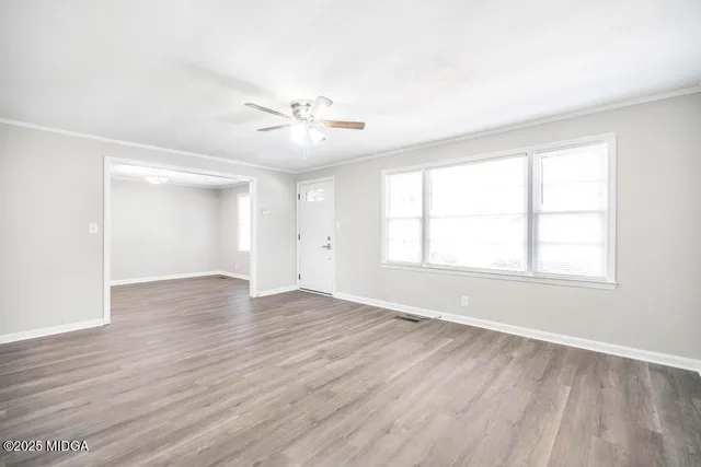 an empty room with wooden floor and windows