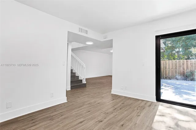 a view of a big room with wooden floor and windows