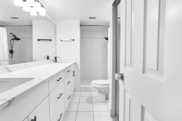 a spacious bathroom with a double vanity sink a toilet and a mirror