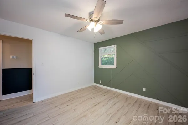 an empty room with wooden floor fan and windows