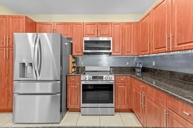 a kitchen with granite countertop a refrigerator stove and microwave