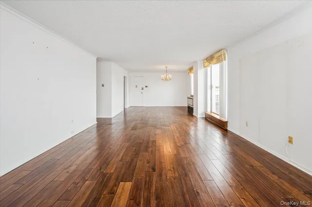 a view of a big room with wooden floor and windows