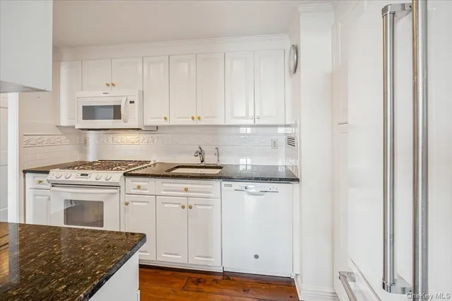 a kitchen with stainless steel appliances granite countertop a stove and a white cabinet