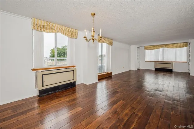 a view of a room with wooden floor a ceiling fan and windows