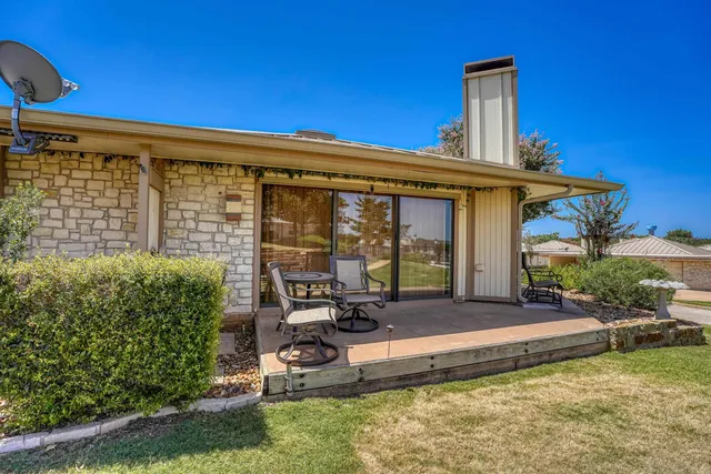 a view of a chair and table in backyard of the house