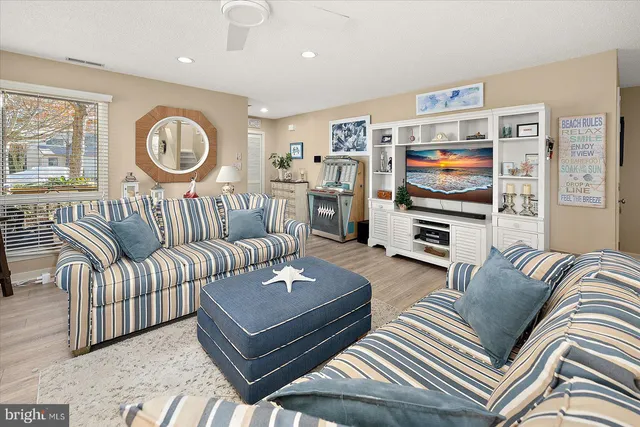 a living room with furniture a flat screen tv and wall paintings