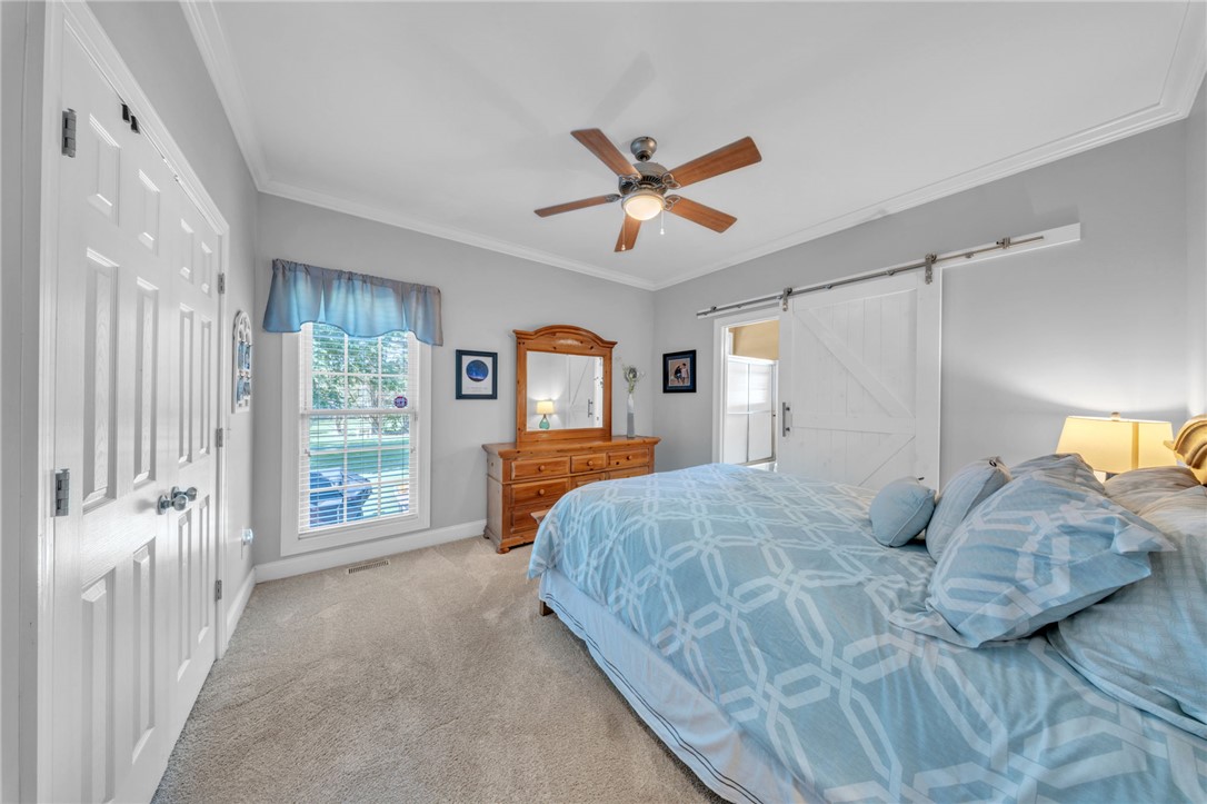 648 Mountain View Road Williamston, SC 29697 - Photo 22 of 42 A well-lit primary bedroom features a ceiling fan, plush carpet, and a stylish barn door leading to an adjoining space.