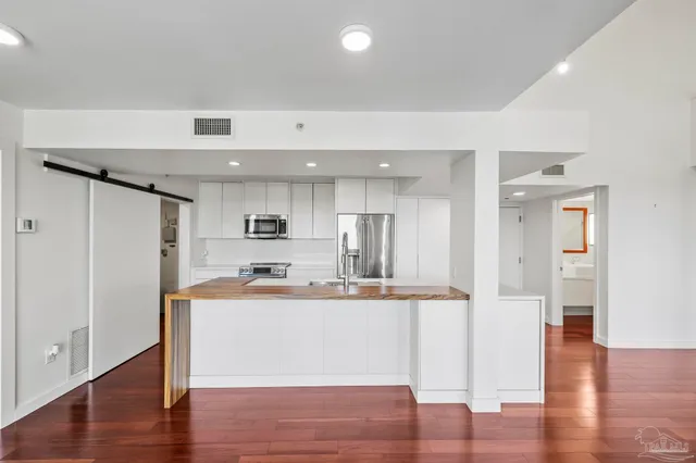 a room with stainless steel appliances kitchen island sink and wooden floor