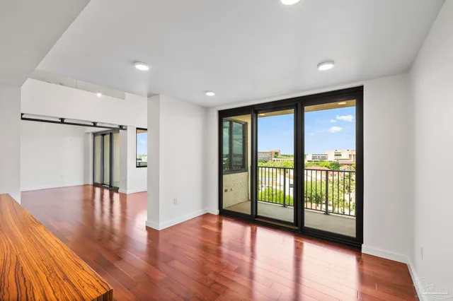 a view of empty room with wooden floor and fan