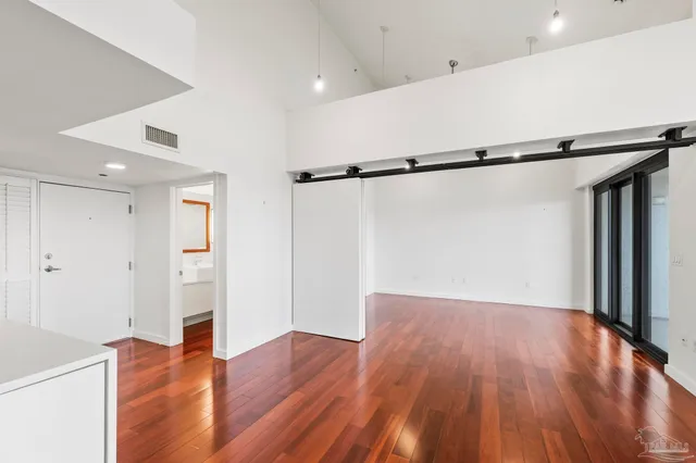 a view of an empty room with wooden floor and a window