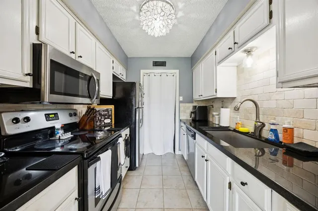 a kitchen with stainless steel appliances granite countertop a sink stove microwave and refrigerator