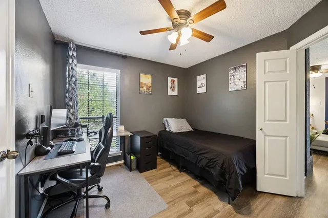 a bedroom with a bed a desk and chair with wooden floor