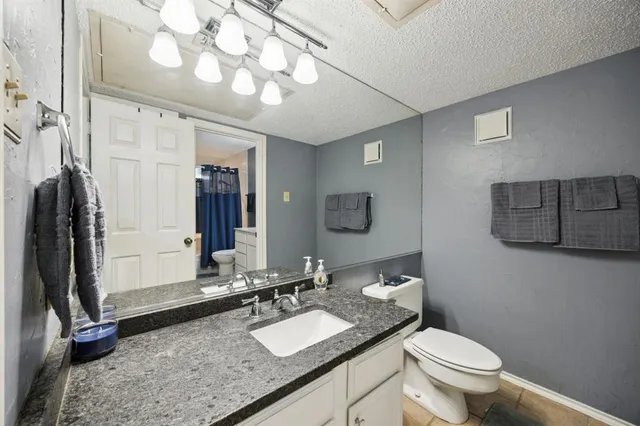 a bathroom with a granite countertop sink mirror vanity and toilet