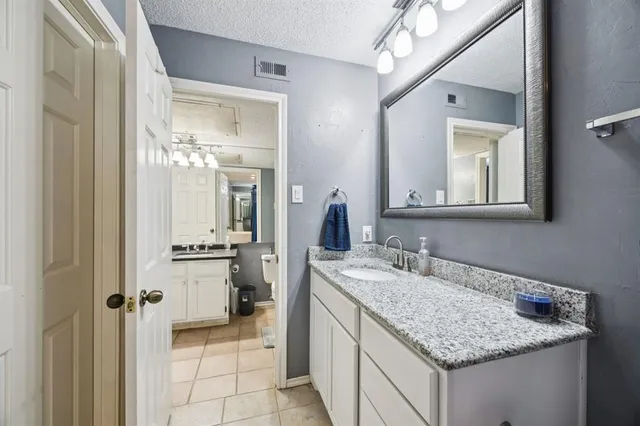 a en suite bathroom with a granite countertop sink and a mirror