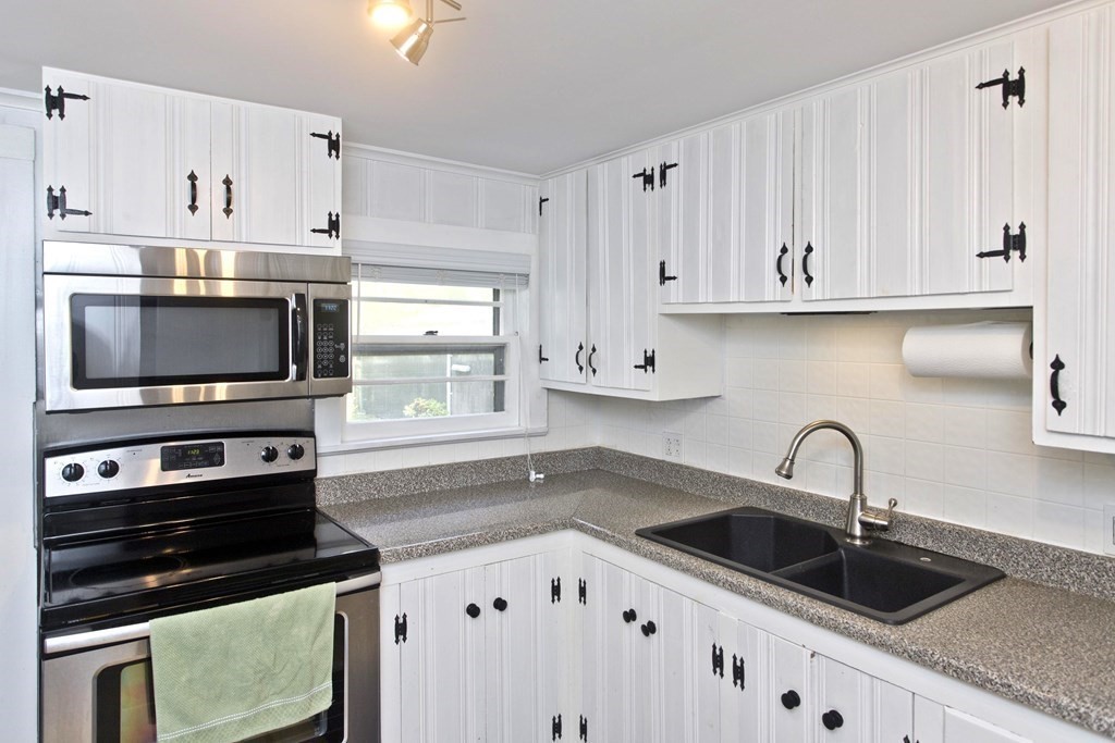 520 Dutchess Street Springfield, MA 01129 - Photo 5 of 31 a kitchen with white cabinets a sink and a stove