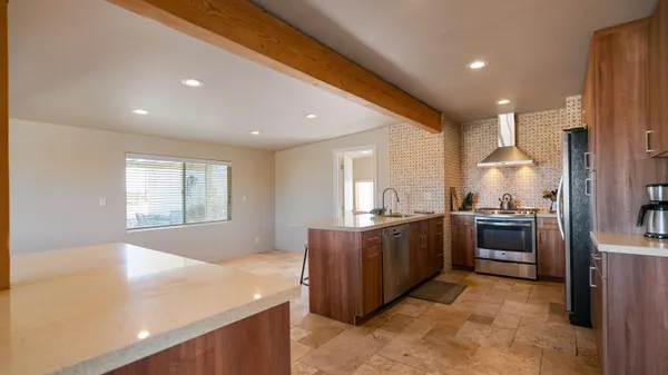 a large kitchen with stainless steel appliances granite countertop a large counter top a stove and a refrigerator