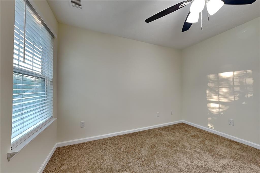1595 Stephens Pond View Loganville, GA 30052 - Photo 13 of 22 en empty room with windows and ceiling fan