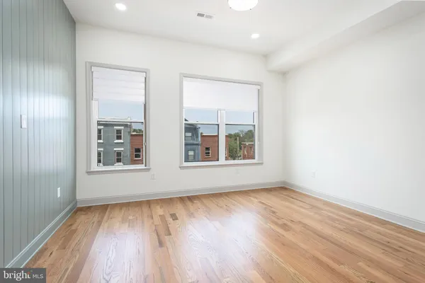 an empty room with wooden floor and windows