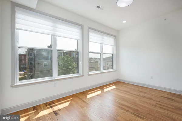 a view of an empty room with wooden floor and a window