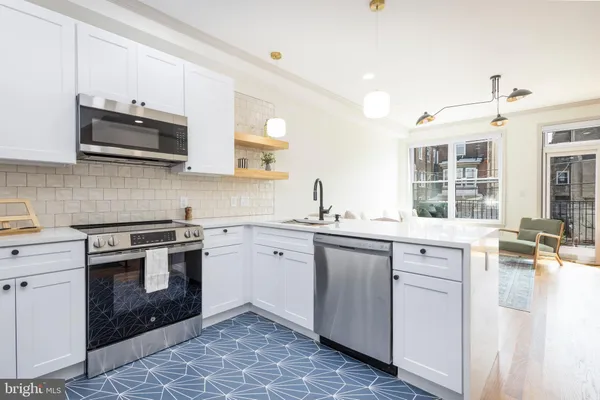 a kitchen with stainless steel appliances granite countertop a stove top oven a sink dishwasher and white cabinets with wooden floor