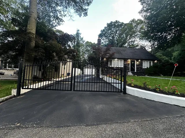 a view of a brick house and a yard with large trees