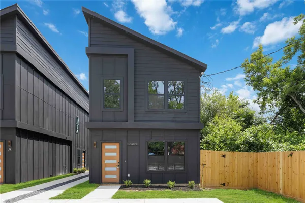 a view of a house with brick walls and a yard with a large tree