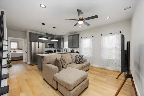 a living room with furniture kitchen view and a wooden floor