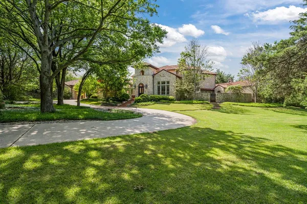 a view of a house with a big yard and large trees
