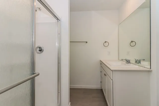 a bathroom with a granite countertop sink a mirror and shower