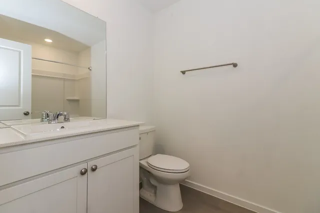 a bathroom with a toilet sink vanity and mirror