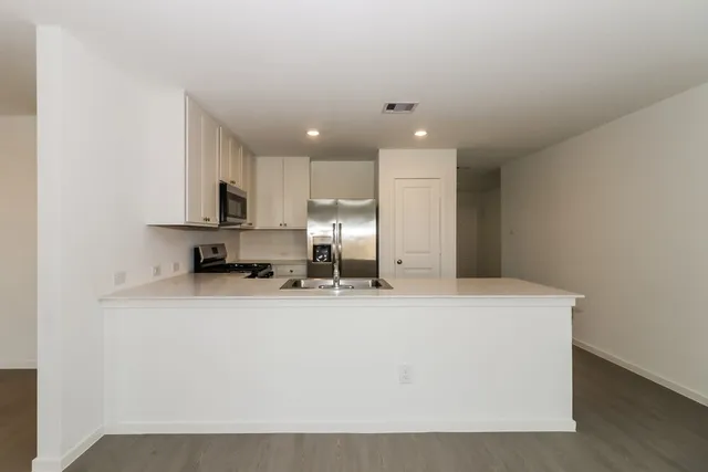 a large kitchen with stainless steel appliances a sink a stove a microwave a sink and cabinets