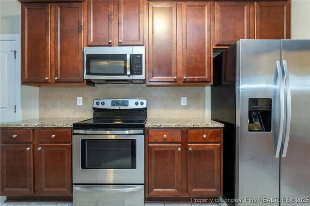 a kitchen with granite countertop wooden cabinets and stainless steel appliances