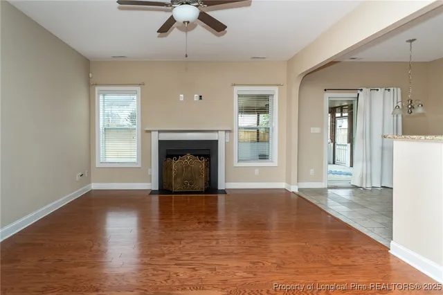 an empty room with wooden floor a fireplace and windows