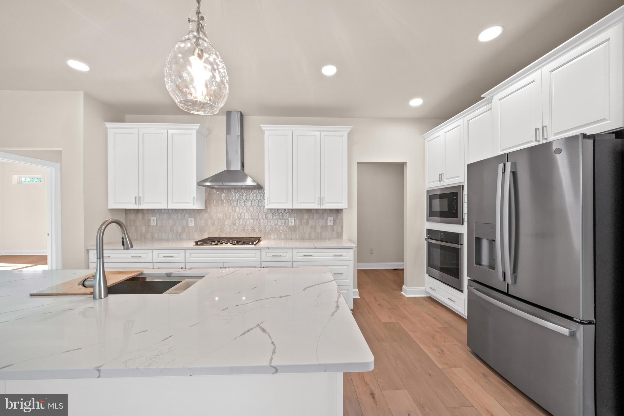 33766 Catching Cove Lewes, DE 19958 - Photo 12 of 47 a kitchen with stainless steel appliances granite countertop a refrigerator stove and wooden floor