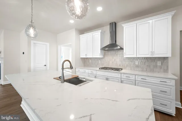 a kitchen with stainless steel appliances granite countertop a stove a sink dishwasher a refrigerator and white cabinets with wooden floor