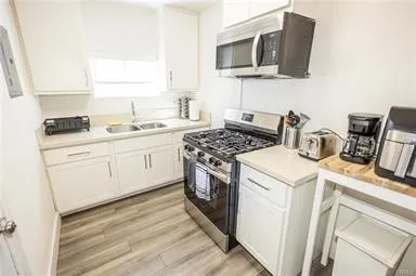 a kitchen with stainless steel appliances granite countertop a sink a stove and microwave with wooden floor