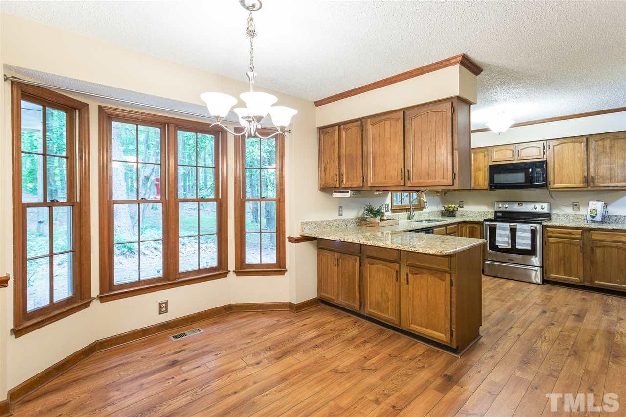 10005 Bavin Place Raleigh, NC 27613 - Photo 7 of 30 a kitchen with stainless steel appliances granite countertop a stove top oven a sink dishwasher and a microwave oven on the wooden floor