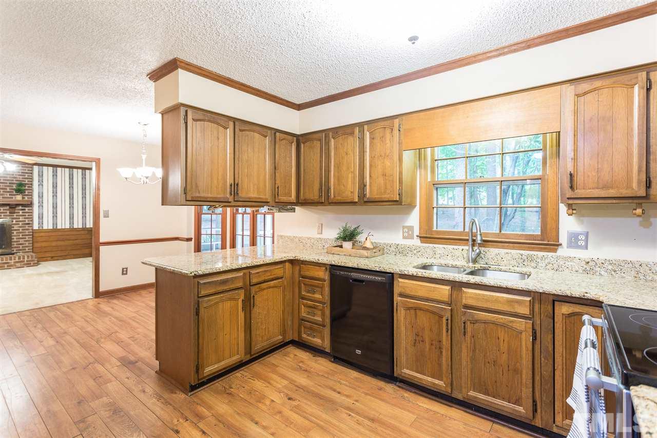10005 Bavin Place Raleigh, NC 27613 - Photo 9 of 30 a kitchen with stainless steel appliances granite countertop wooden cabinets a sink and dishwasher with wooden floor