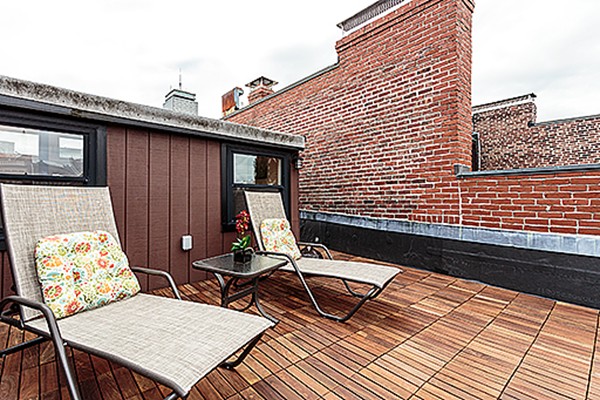 a roof deck with a chair and potted plants