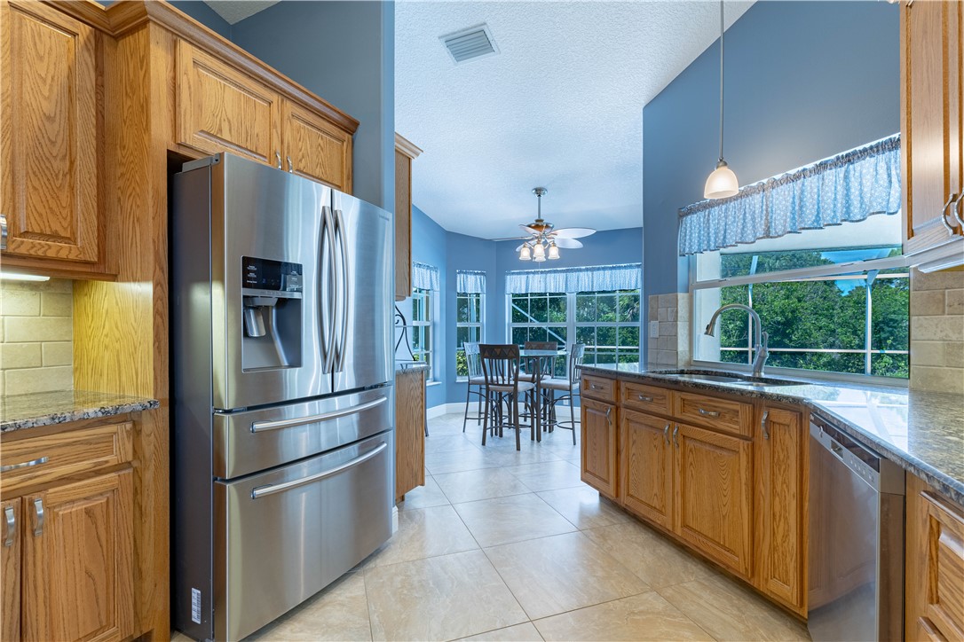 414 Ash Street Sebastian, FL 32958 - Photo 6 of 36 a kitchen with stainless steel appliances granite countertop a refrigerator a sink a stove and a refrigerator with wooden floor