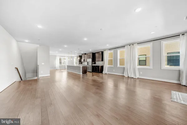 a view of an empty room with wooden floor and windows