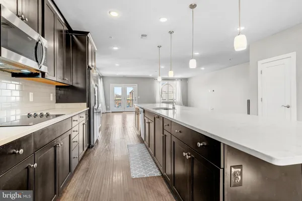 a kitchen with stainless steel appliances lots of counter space wooden floor and sink