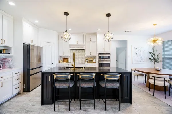 a kitchen with stainless steel appliances a table chairs refrigerator and cabinets